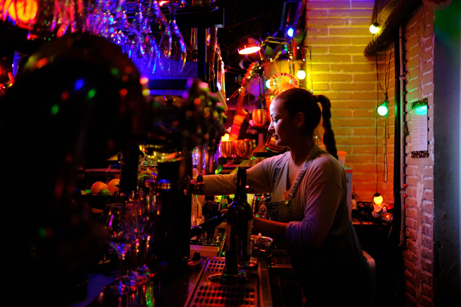 Young female bartender working behind the counter of a bar.